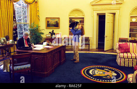 12/24/1994 - Foto von Chelsea Clinton Spielen mit Socken die Katze im Oval Office, während Präsident William Jefferson Clinton arbeitet an seinem Schreibtisch Stockfoto