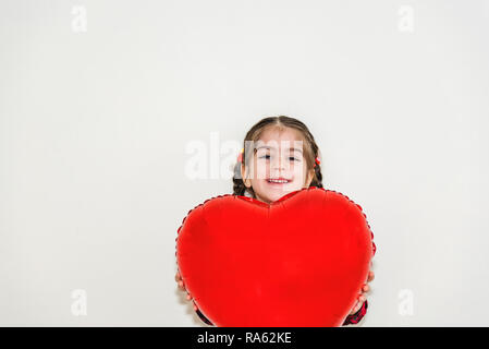 Adorable reizendes kleines Mädchen hält rote herzförmige Ballons. Urlaub-Konzept mit isolierten Hintergrund Stockfoto