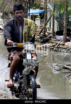 Ein indonesischer Mann Fahrten durch den Schutt gefüllte Straßen, die durch den Tsunami, Banda Aceh, Sumatra, Indonesien (IDN) zerstört, verwüstet wurden. Stockfoto