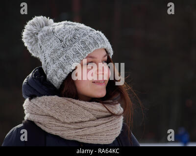 Glückliche junge Frau im Winter Mütze und Schal im Winter Park im sonnigen Tag Stockfoto