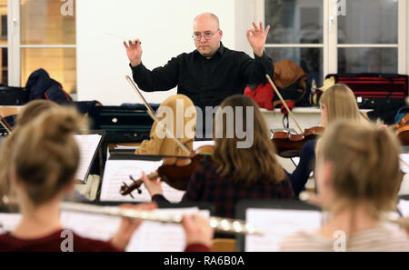 Schwerin, Deutschland. 19 Dez, 2018. Dirigent Stefan Kerber und der Schweriner Youth Symphony Orchestra im Chaos die Probe, die erste Probe des Orchesters. Das Orchester mit über 60 Mädchen und Jungen zwischen 12 und 19 spielt Stücke für ein neues Programm für das erste Mal im Alter. Schätzungen zufolge mehr als 150.000 Kinder spielen in etwa 5000 Kinder- und Jugendorchestern in Deutschland. Sie reichen von einfachen Spielen Kreisen zu vollständigen Symphonieorchester. Quelle: Bernd Wüstneck/dpa/Alamy leben Nachrichten Stockfoto