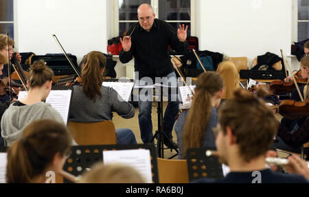 Schwerin, Deutschland. 19 Dez, 2018. Dirigent Stefan Kerber und der Schweriner Youth Symphony Orchestra im Chaos die Probe, die erste Probe des Orchesters. Das Orchester mit über 60 Mädchen und Jungen zwischen 12 und 19 spielt Stücke für ein neues Programm für das erste Mal im Alter. Schätzungen zufolge mehr als 150.000 Kinder spielen in etwa 5000 Kinder- und Jugendorchestern in Deutschland. Sie reichen von einfachen Spielen Kreisen zu vollständigen Symphonieorchester. Quelle: Bernd Wüstneck/dpa/Alamy leben Nachrichten Stockfoto