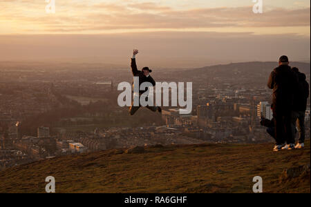 Edinburgh, Schottland, Großbritannien. 2. Januar 2019. UK Wetter, Touristen genießen die Aussicht von Arthur's Seat Gipfel in Holyrood Park gleich um Sonnenuntergang, obwohl die Temperatur minus 1 Grad nach einer Nacht von minus sechs Grad. Stockfoto