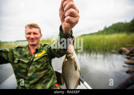 Der Mensch in der Tarnung Angelrute auf dem Fluss auf einem Schlauchboot. Stockfoto