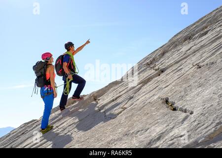Bergführer führt eine junge Frau auf einem kurzen Seil durch eine Felswand, Wiederroute, Watzmann, Schönau am Königssee Stockfoto