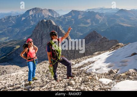 Bergführer führt eine junge Frau auf einem kurzen Seil durch eine Felswand, Wiederroute, Watzmann, Schönau am Königssee Stockfoto