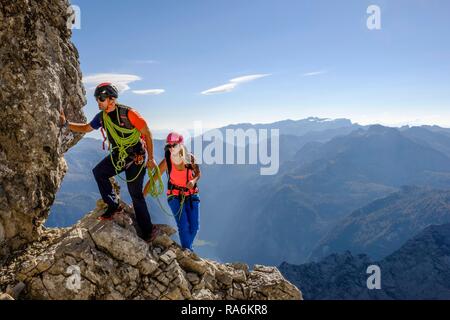 Bergführer führt eine junge Frau auf einem kurzen Seil durch eine Felswand, Wiederroute, Watzmann, Schönau am Königssee Stockfoto