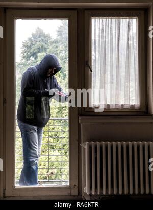 Symbol Bild von Einbruch, Täter versucht, in eine Wohnung zu brechen, nimmt ein Fenster mit einem Werkzeug, Deutschland Stockfoto