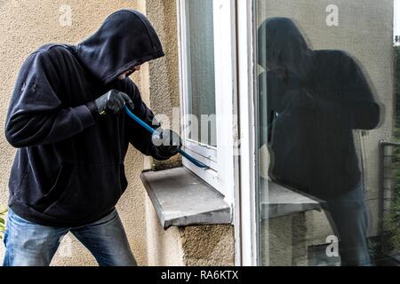 Symbol Bild von Einbruch, Täter versucht, in eine Wohnung zu brechen, nimmt ein Fenster mit einem Werkzeug, Deutschland Stockfoto