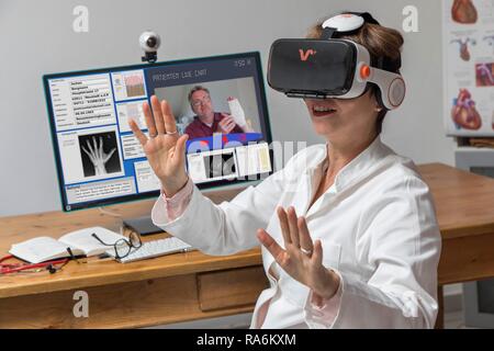 Symbol Foto für Telemedizin, Arzt in einer Praxis, mit VR-Brille, Virtual Reality, 3D-Darstellung eines MRT-Ergebnis, Stockfoto