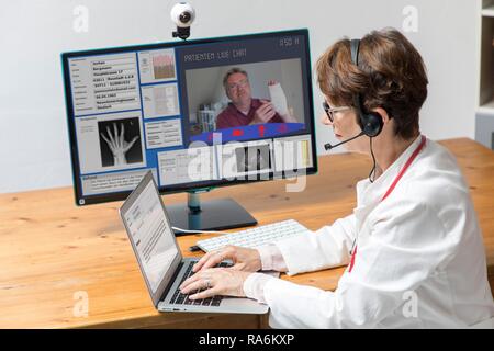 Symbol Foto für Telemedizin, Arzt in einer Praxis, kommuniziert mit dem Patienten über eine Webcam, Patientendaten und Befunde auf Stockfoto
