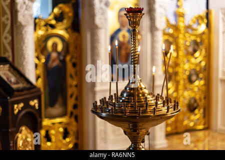 Viele brennende Kerzen in der orthodoxen Kirche oder Tempel auf goldenen Warmen Hintergrund Stockfoto