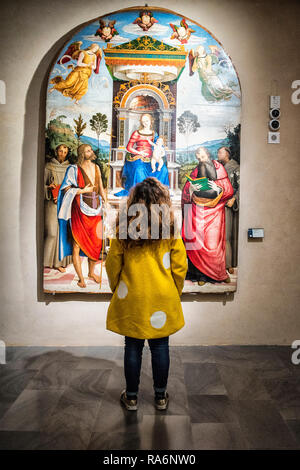 Nationalgalerie von Umbrien, Perugia, Umbrien, Italien. Ein Mädchen mit einem gelben Mantel von den Schultern bewundert ein riesiges Bild. Stockfoto