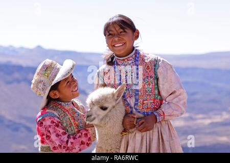 Zwei Mädchen in traditioneller Kleidung mit einem Alpaka, in der Nähe von Arequipa, Peru Stockfoto