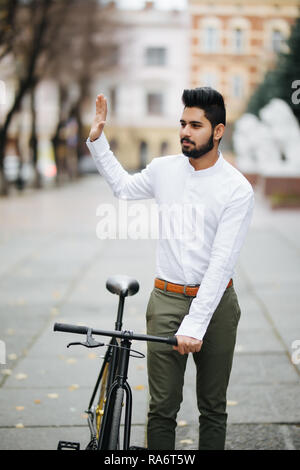 Junge hipster Mann mit fixed Gear bike winkende Hand auf Stadt. Stockfoto