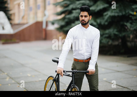 Portrait von indischen Mann mit dem braunen Haar zu Fuß mit dem Fahrrad auf der Straße Stockfoto