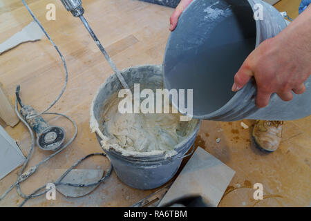 Zement mischen mit einer elektrischen Bohrmaschine Fliesenkleber in einen Eimer für Tiling Stockfoto