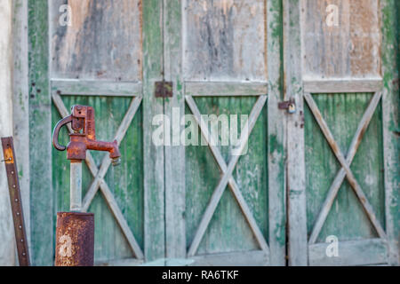 Vintage Tankstelle Pumpe vor Hintergrund der alten grünen Holz Garagentor Stockfoto