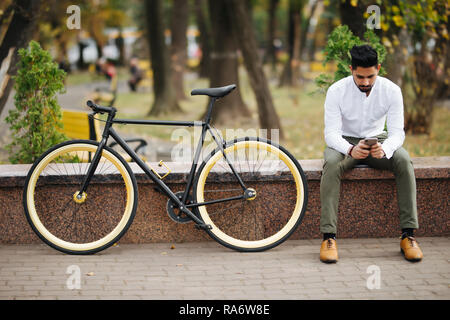 Lifestyle, Verkehr, Kommunikation, Personen Konzept - Junger Mann mit Fahrrad und Smartphone auf Stadt. Stockfoto