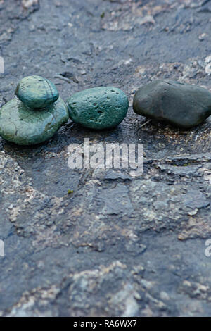 Steinplatte mit kleinen grünen und schwarzen Felsen Stockfoto