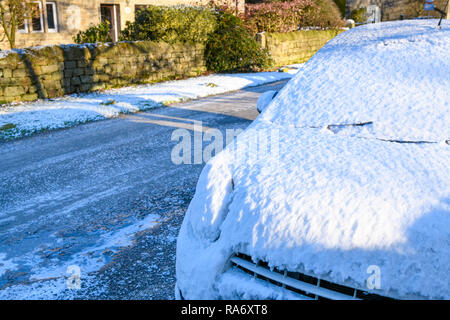 In der Nähe von Schnee bedeckt Auto auf eisglatter Straße der kleinen ländlichen Dorf auf eiskalten schneereichen Winter Tag geparkt - Timble, North Yorkshire, England, Großbritannien Stockfoto