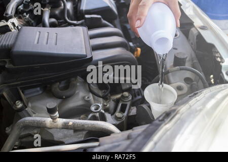 Mechaniker Füllung Wasser für die Scheibenwaschanlagenflüssigkeit zu einem Auto in der Garage. Stockfoto