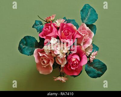 Blumenstrauß aus künstlichen Blumen und grüne Blätter von oben mit einem grünen Hintergrund Stockfoto