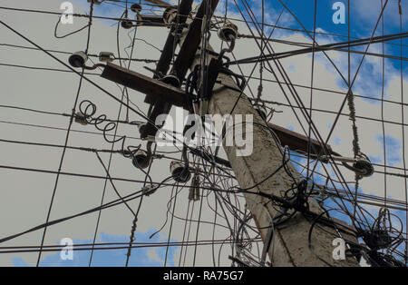 Konkrete elektrische Pole gegen den blauen Himmel mit Wolken. Ein Kabel an eine Säule und blauer Himmel. Stockfoto