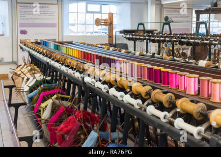 Whitchurch Silk Mill in Hampshire, Großbritannien. Innenraum des Museums mit bunten Garnen auf Rollen oder Spulen aufgewickelt. Stockfoto