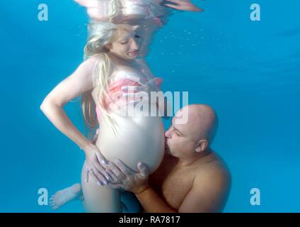 Schwangere Frau und Mann, Unterwasser Mode in einem Pool Stockfoto