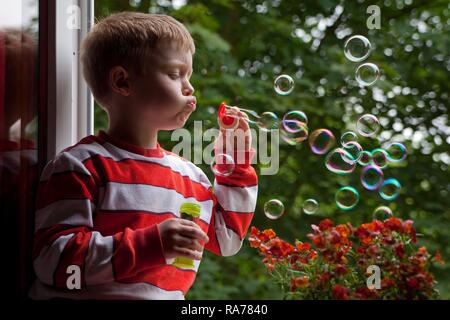 Kleiner Junge bläst Seifenblasen Stockfoto