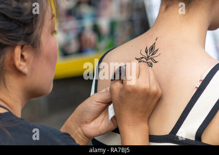 Tourist in Thailand bekommt ein Rückentattoo von einem thailändischen Künstler. Stockfoto