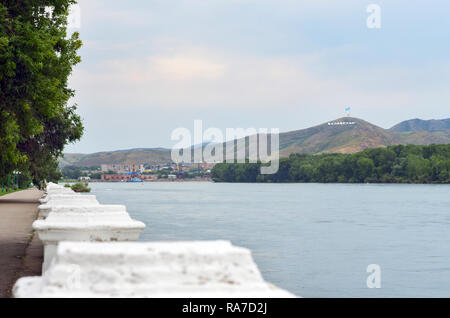 (Oskemen Ust-Kamenogorsk in Kasachstan), Kasachstan - Juli 10, 2017. Irtysch River Embankment, Hafenkräne, Wohnblocks und Häusern und Ablaketka Stockfoto