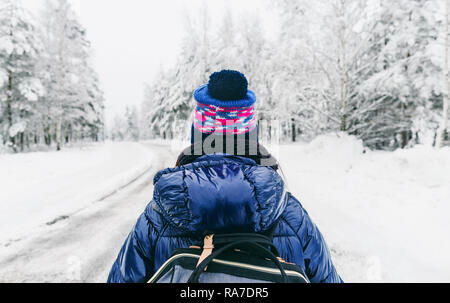Reisen Lifestyle. Junge Frau mit Rucksack im Winter auf verschneiten Straßen in Schweden Stockfoto