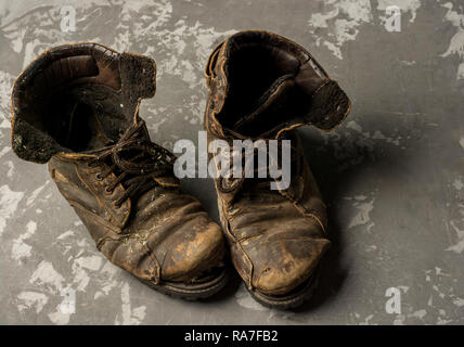 Alte Stiefel auf konkreten Hintergrund, Vintage Konzept Stockfoto