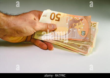 Mann Hand, die Haufen von 50 Euro Rechnungen Reichtum in einem Geschäft zu zeigen. Stockfoto