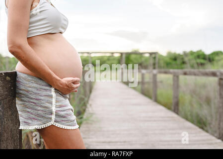 In der Nähe von schwangeren Bauch streicheln mit ihren Händen in der Natur. Stockfoto