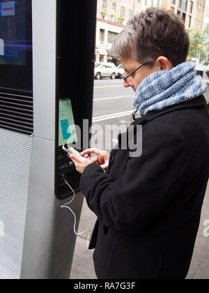 Frau mit LinkNYC Ladestation, Oktober 2018, © katharine Andriotis Stockfoto