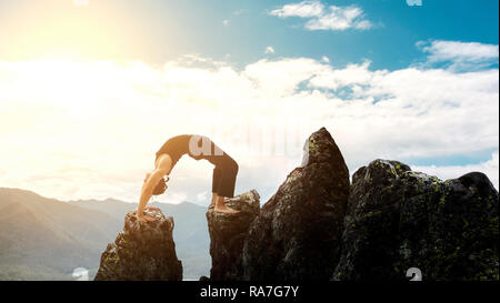 Mann tun, komplexe Yogaübung Kopfstand. Erstaunlich Yoga Landschaft in herrlicher Bergwelt. Gefährliche stunts Traceur stehend auf seine Hände auf den Rand einer Klippe. Stockfoto