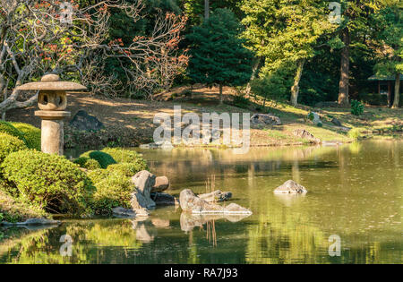 Steinlaterne am Ufer des Daisensui-Teiches in den Rikugien-Gärten, Tokio, Japan Stockfoto