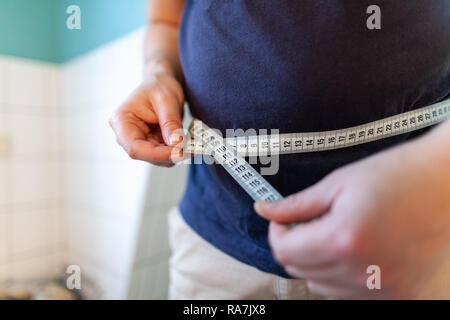 Man Maßnahmen ihr Bauch mit einem Maßband Stockfoto