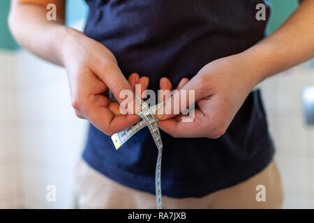 Man Maßnahmen ihr Bauch mit einem Maßband Stockfoto