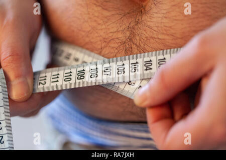 Man Maßnahmen ihr Bauch mit einem Maßband Stockfoto