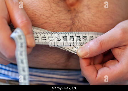 Man Maßnahmen ihr Bauch mit einem Maßband Stockfoto