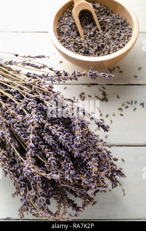 Bündel von getrocknetem Lavendel Kräuter ruht auf Weiß lackiert Holz beplankt, mit Schale der Blütenknospen und woden Lufthutze in Soft Focus Hintergrund.. Stockfoto