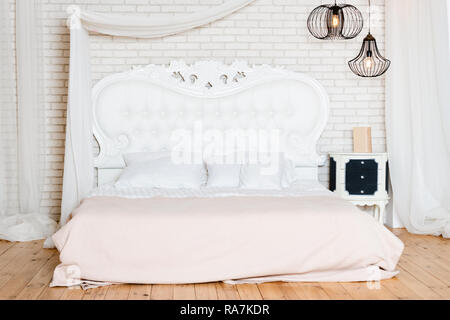 King size Bett im Loft Apartment. Schlafzimmer im Loftstil mit weißem Design Stockfoto