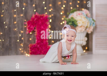 Cute Baby Mädchen 1-2 Jahre alten sitzen auf dem Boden mit rosa Luftballons im Zimmer über Weiß. Isoliert. Geburtstag. Feier. Happy birthday Baby, ein wenig Stockfoto