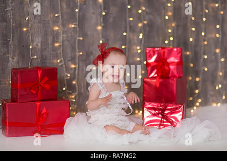 Cute Baby Mädchen 1-2 Jahre alten sitzen auf dem Boden mit rosa Luftballons im Zimmer über Weiß. Isoliert. Geburtstag. Feier. Happy birthday Baby, ein wenig Stockfoto