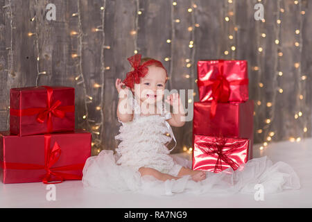 Cute Baby Mädchen 1-2 Jahre alten sitzen auf dem Boden mit rosa Luftballons im Zimmer über Weiß. Isoliert. Geburtstag. Feier. Happy birthday Baby, ein wenig Stockfoto