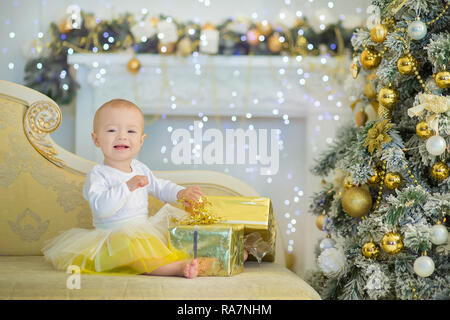 Cute Baby Mädchen 1-2 Jahre alten sitzen auf dem Boden mit rosa Luftballons im Zimmer über Weiß. Isoliert. Geburtstag. Feier. Happy birthday Baby, ein wenig Stockfoto